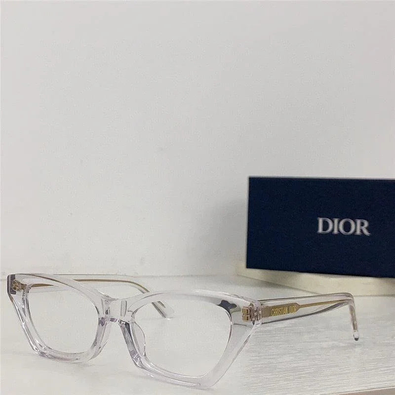Clear cat eye eyeglasses with transparent frame on white surface, DIOR box in background